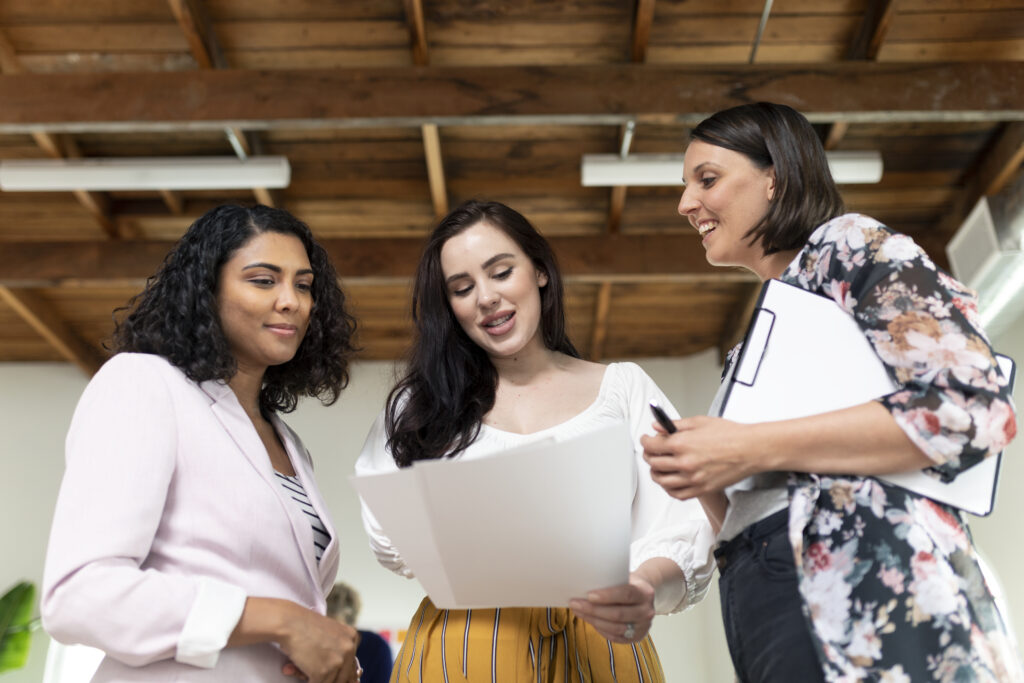 Une étudiante en alternance montrant des éléments créatifs à son maître de stage et sa collègue.